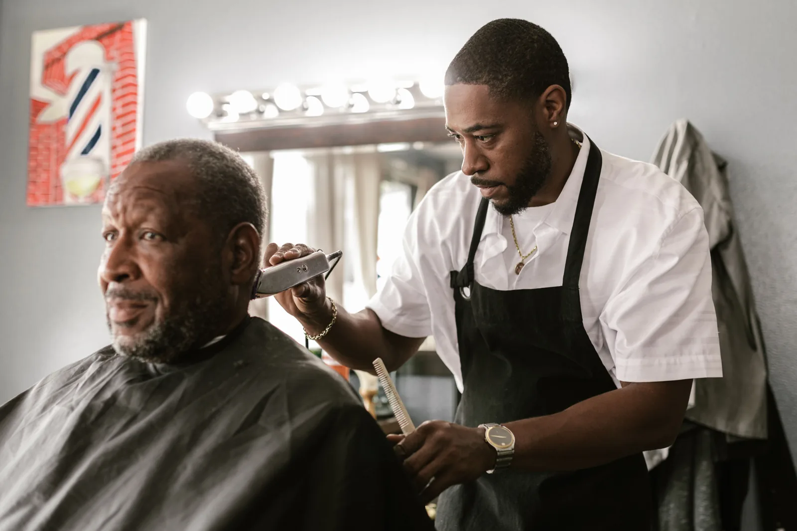 A barber trimming a client's hair in a barbershop; stock concept photograph