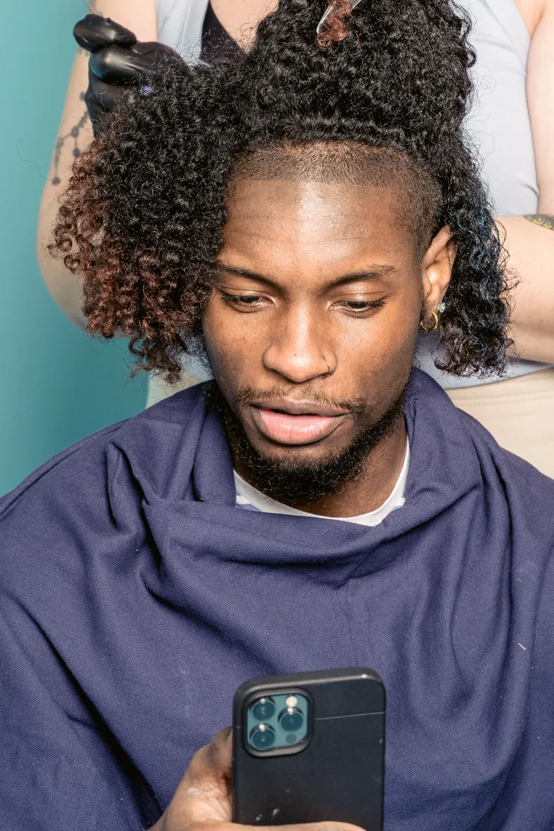 A client with textured curly hair seated in a barbershop; stock inspiration photograph