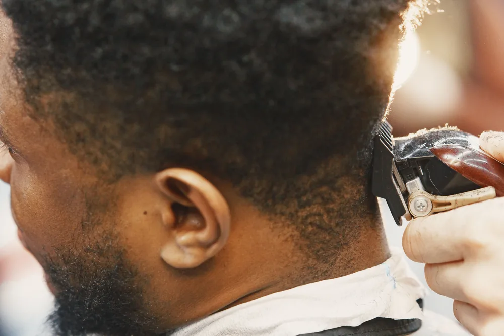 Close-up of a barber using clippers around a client's ear; stock inspiration photograph